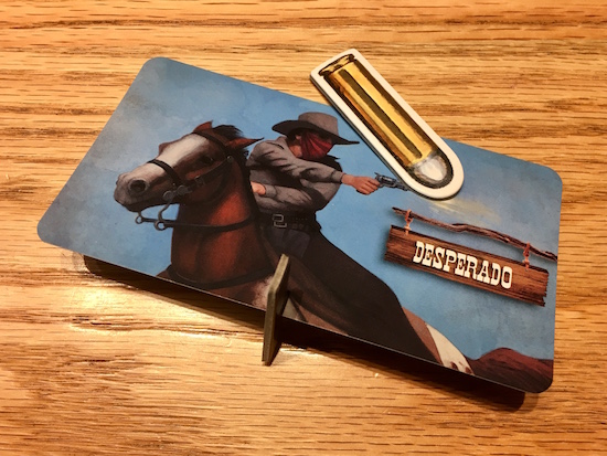 A desperado card with a card stock base knocked over by a card stock bullet. 