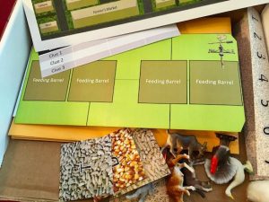 Puzzle components including tiles with animal feed, little plastic farm animals, and farm maps.