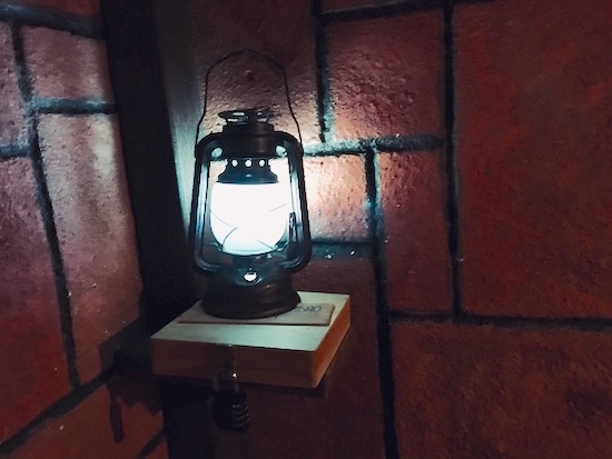 In-game: a glowing lantern resting on a lock box in a stone tunnel.