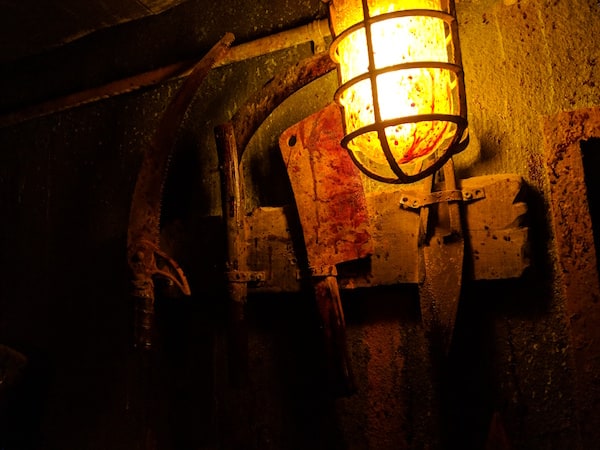 In-game: Bloodied tools and kitchen knives hanging on a wall.