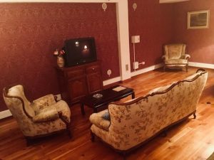 In-game: The living room of 1408, an old space with large, dated furniture and a television.