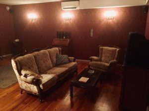 In-game: The living room of 1408, an old space with large, dated furniture and a television.