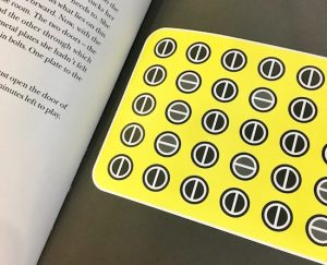 In-book, page shows the first puzzle: a grid of circles that look like flat-head screwheads, some oriented vertically, others, horizontally.