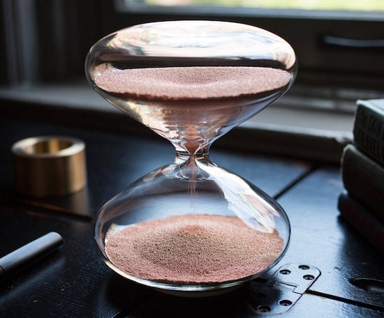 A beautiful glass hourglass with copper ballbearings inside as sand.