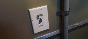 An electrical outlet with a blue do not touch sticker.