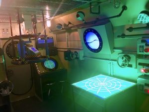 In-game: The bridge of the submarine. A map glows green.