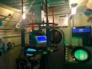 In-game: The bridge of the submarine. A sonar station and periscope are in view.