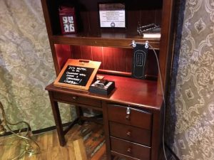 In-game: a desk with assorted items and a strange wire running from it.