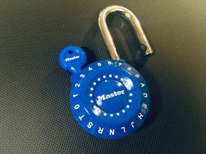 Blue alphanumeric locker-style padlock open with a reset key inserted.