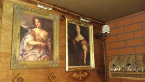 In-game: two paintings next to a shelf with bottles containing liquid.