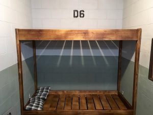 In-game: A bunk bed in a concrete prison cell.