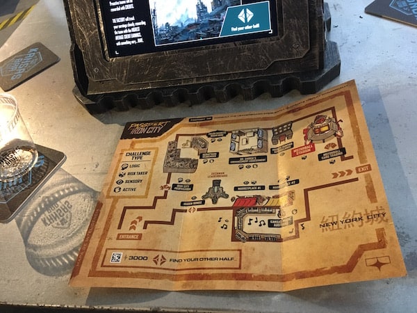 In-game: an empty "Kansas Bar" glass beside a map of Iron City and an illuminated touchscreen.