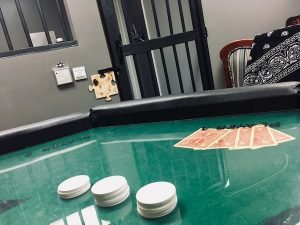 In-game: Shot over a poker table, a gated doorway in the background.