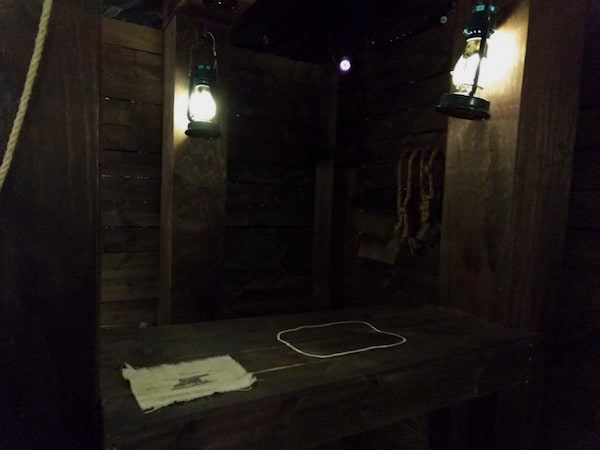 In-game: A table with a map on it inside of a lantern-lit pirate ship.