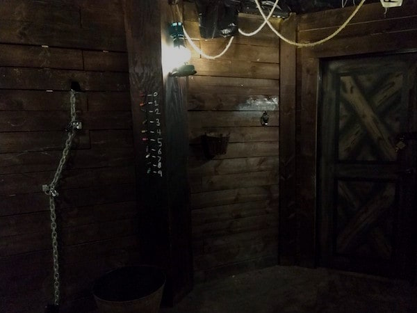 In-game: The inside of a pirate ship There are ropes and chains running from the ceiling and walls, and number painted into a beam.