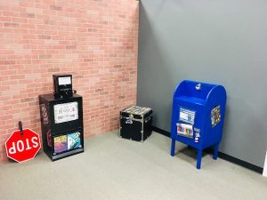 In-game: A brick facade, a newspaper vending machine, a handheld stop sign, a blue mailbox.