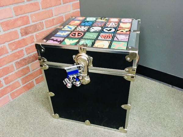 In-game: A trunk with 20 super hero logos on the top, sealed with two combination locks.