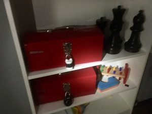 In-game: 2 locked toolboxes beside children's toys in a dark room.