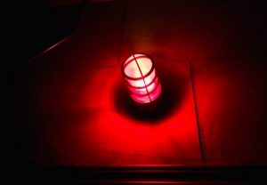 In-game: Closeup of a glowing red light in a dark room.