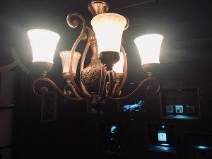 In-game: An ornate chandelier with magical props illuminated in the background.