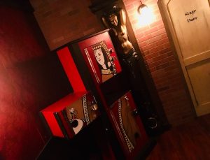 In-game: A magic prop with the image of a queen on it beside a gold art deco statue of a nude woman and the stage door.