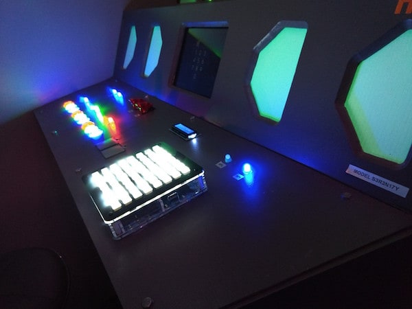 In-game: A space ship control panel with multi-colored glowing buttons.