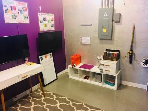 In-game: A silver and purple room with televisions ikea furniture, and locked boxes.