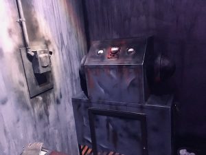 In-game: a large piece of metal machinery in a heavily worn concrete bunker.