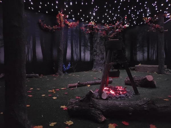 In-game: A campfire burning under the stars in the middle of the autumn woods.