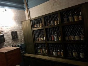 In-game: A view behind the bar at a wall of liquor.