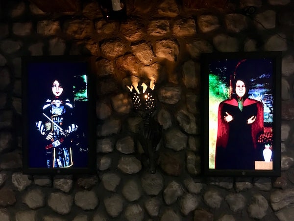 In-game: Animated paintings hanging from a stone wall.