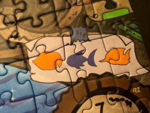 Closeup of a puzzle element depicting three different types of fish.