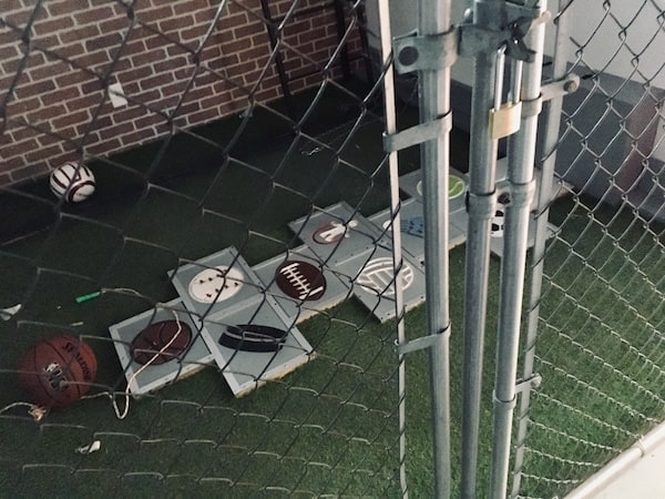 In-game: A hopscotch with each tile bearing a piece of sporting equipment shot through the gate of a schoolyard.