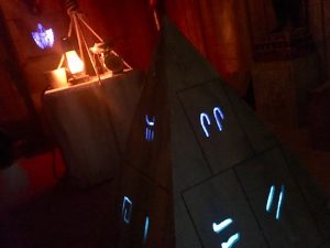 In-game: A pyramid with glowing symbols in the middle of a tomb excavation site.