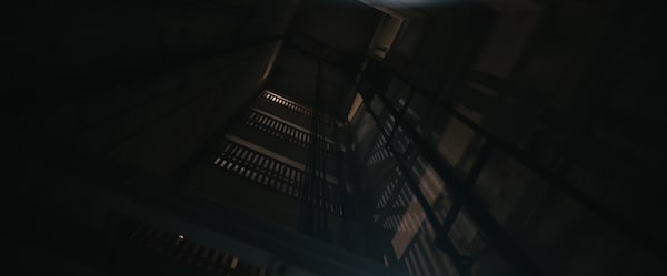 A view of an old freight elevator shaft with dramatic shadows being cast against the walls.