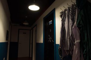 In-game: The hallway of an asylum with patient clothes hanging from hooks on the wall.