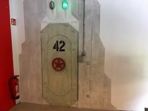 The entry to the game, a steel door labeled 42 with a red wheel.