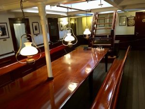 A beautiful long wooden table in the middle of the crew's quarters.