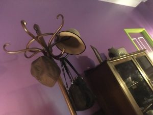 In-game: a coat rack with a pair of hats and a handbag hanging from it.