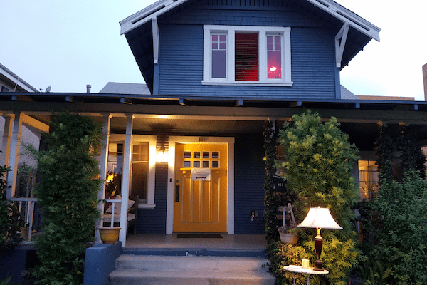 The haunted house, a beautiful blue and white house with a yellow door and a porch.