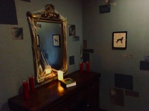 In-game: a spooky mirror flanked candles above a dresser.