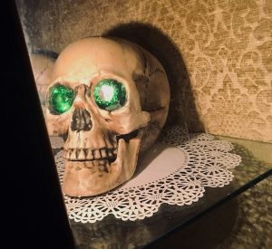 In-game: a human skull with emeralds in its eye sockets resting on a doily.