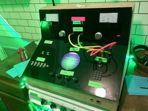 In-game: An unusual device with buttons, dials, switches, and screens.