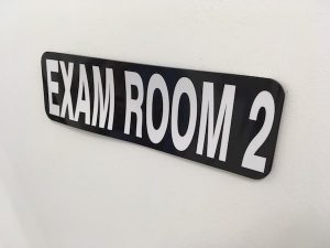 In-game: closeup of the "Exam Room 2" sign.