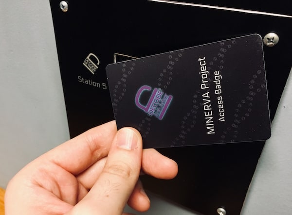In-game: a "MINERVA Project Access Badge" held up to a scanning station.