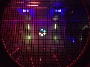 In-game: A hexagon made from multicolored glowing hexagons surrounded by lasers.