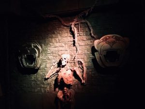 In-game: A human skeleton hanging from a wall between two panther sculptures.