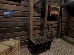 In-game: the approach to a mine shaft, the floor has trunks filled with mining gear.