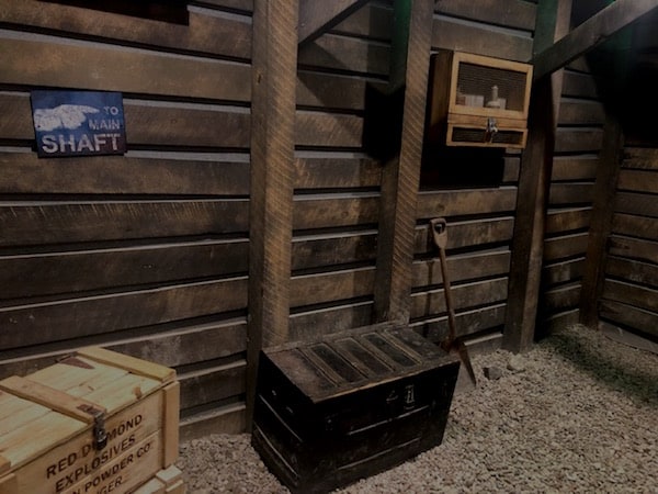 In-game: the approach to a mine shaft, the floor has trunks filled with mining gear.