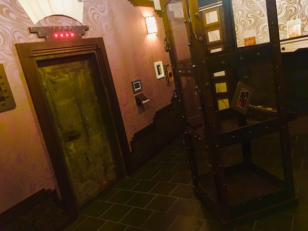 In-game: Wide angle shot of the room, a water torture chamber in the middle of it.